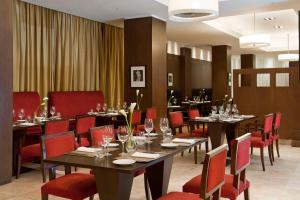 布宜诺斯艾利斯NH布宜诺斯艾利斯城市酒店的用餐室配有长桌子和红色椅子