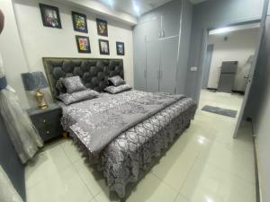 拉合尔The Bahria Town Hotel & Suites的一间卧室配有一张大床和灰色的被子