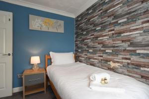 朴次茅斯Spacious 4-Bed Family House的一间卧室设有一张床和砖墙