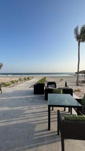 塞拉莱Hawana salalah Apartment Acacia的一个带桌椅的海滩和棕榈树