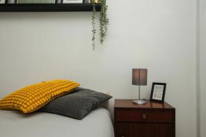 里斯本Low Cost Subway Privado的一间卧室配有一张带黄色枕头和床头柜的床