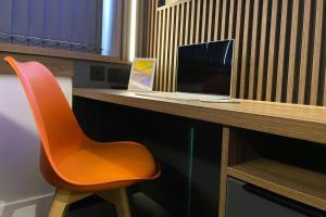 莱斯特Deluxe 1 Bed Studio 4C near Royal Infirmary & DMU的一张桌子上的橙色椅子和笔记本电脑
