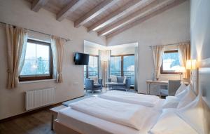 佩尔蒂绍Hotel der Wiesenhof的一间带白色床的卧室和一间带椅子的房间