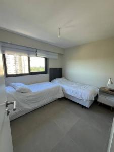 埃斯特角城Alquiler Apto Punta Del Este的一间卧室设有两张床和窗户。