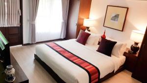 清迈清迈兰特瑞酒店的卧室配有带红色枕头的大型白色床
