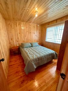 瓦尔迪维亚Cabañas Vista al Mar的木制客房内的一间卧室,配有一张床