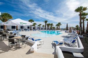 卡门港全景公寓酒店 - 仅限成人入住的游泳池设有蓝白色椅子和桌子,棕榈树