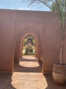 马拉喀什Villa Pauline with private pool & garden, hotel service and no insight.的走廊上有一个拱门,里面种有植物