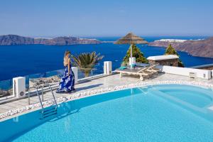 易莫洛林Santorini Princess Spa Hotel的身着蓝色衣服的女人站在游泳池旁