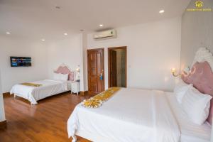 绥和市Hoàng Gia Hotel Tuy Hoà的一间卧室配有两张带白色床单和粉红色长袍的床。