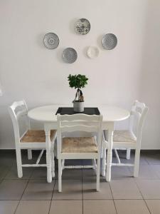 利马索尔Nostalgia apts的白色的桌子和椅子,上面有盆栽植物