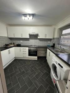 HornchurchCosy Spacious 2 bed flat Hornchurch high street的厨房配有白色橱柜、洗衣机和水槽