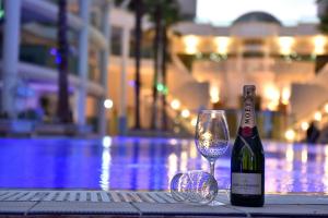 埃拉特פנטהאוז בפלמורה的一瓶葡萄酒和泳池旁的一杯