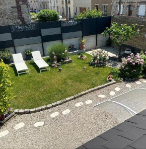 兰斯La Petite Maison de Jane的花园设有两把椅子和一些鲜花
