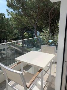 利尼亚诺萨比亚多罗Suite Erica Lignano Hotel的阳台上配有一张白色的桌子和两把椅子