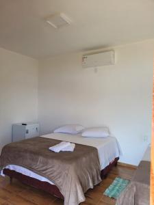 德尔菲诺波利斯Chalé Praia Vermelha 1的卧室配有一张带白色墙壁的大床
