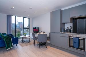 曼彻斯特City Cosy 1 bed - Perfect for Long Stays By Valore Property Services的厨房以及带桌椅的起居室。
