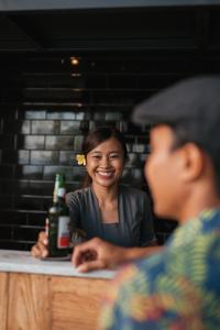 卡朗阿森East Bali Volcano View Resort & Spa - Adults Only Area的坐在桌子旁的女人,喝一瓶啤酒