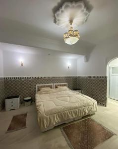 La rose des sables的一间卧室配有一张大床和一个吊灯。