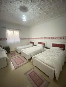 La rose des sables的一间卧室设有三张床和天花板