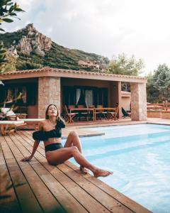 帕拉迪索海岸Costa Paradiso Resort的坐在游泳池旁甲板上的比基尼的女人