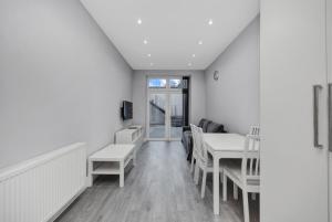 伦敦Your Cosy Stay Modern 3 Double Bedroom Apartment - Fully Furnished - 5 Mins walk to Stn的白色的客房配有桌椅