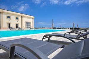 马尔扎梅米Dimora Savarino Marzamemi Suites with pool的一组椅子坐在游泳池旁