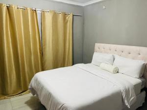 马翁Partulaka Rest Inn的卧室配有一张白色大床和黄色窗帘