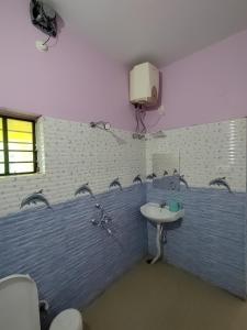 博尔普尔Muktomon Hotel & Resort的一间带水槽的浴室和墙上的电视