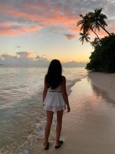 费利杜Alimas Holiday Retreat Maldives的站在海滩上看日落的小女孩