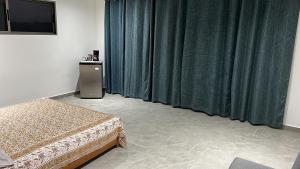 卡里略Casa yin yang的一间卧室配有绿色窗帘、一张床和电视