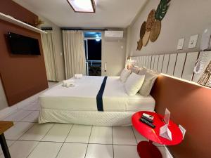 巴雷里尼亚斯Gran Lençóis Flat Barreirinhas APT 510的一间卧室设有一张大床和一张红色的桌子。