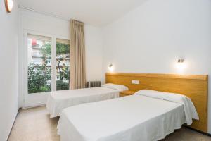 布拉内斯Apartamentos Blanes-Condal Costa Brava的带窗户的客房内的两张床