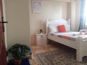尼耶利MT. KENYA PALACE的卧室配有白色的床和植物