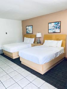 Locust ValleyTides Inn at Stehli Beach的配有白色床单的酒店客房内的两张床