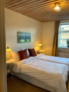 吉利勒杰Gilbjerg Strandhotel的卧室配有一张带两张桌子的大型白色床
