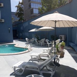 圣地亚哥阿尔卡拉德尔里奥酒店的一组躺椅和一把遮阳伞,位于游泳池旁