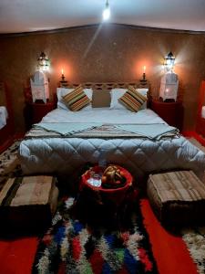 El GoueraChegaga Luxury Camp的卧室配有一张大床,墙上有两盏灯