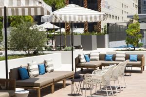 洛杉矶Level Los Angeles - Downtown South Olive的天井配有沙发、椅子和遮阳伞