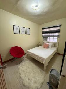 独鲁万2 Bedroom Guest Suite Near The New EVRMC Hospital & San Juanico Bridge Tacloban City, Leyte, Philippines的一间卧室配有一张床和一张红色椅子