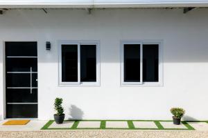 Santa ElenaCasa Valencia 2的白色的房子,有两个窗户和两个盆栽植物