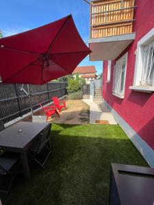 米洛Maison rouge的一个带桌子和红色遮阳伞的庭院