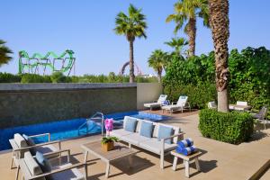 迪拜拉皮塔迪拜主题乐园及度假村 - 万豪酒店&度假村的一个带椅子的庭院和一个棕榈树游泳池