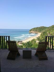 蓬塔米塔蓬德美达伊玛塔度假酒店的俯瞰海滩的阳台配有两把椅子和一张桌子