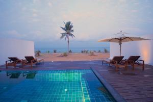 尼甘布杰特威塔拉赫纳别墅酒店的一个带椅子和遮阳伞的游泳池以及海滩