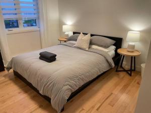 魁北克市Le Citadin - Maison neuve moderne & ensoleillée的一间卧室配有一张带两张桌子和两盏灯的床。