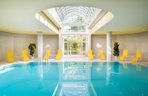 魏玛魏玛莱昂纳多酒店的一个带黄色椅子和大窗户的游泳池