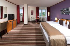 魏玛魏玛莱昂纳多酒店的一间酒店客房,配有一张大床和一台平面电视