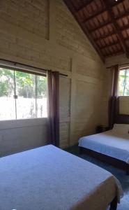卡瓦坎特Chalé da Serra的一间卧室设有两张床和大窗户