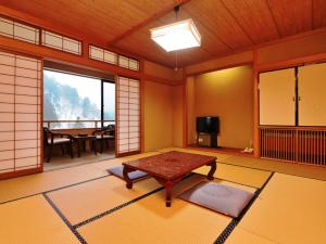 高山汤之平旅馆的日式客房配有桌子和电视